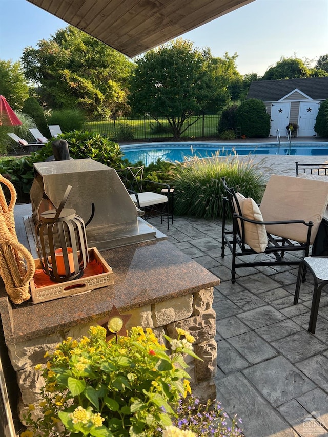 view of patio / terrace featuring a fenced in pool, a fenced backyard, and an outdoor kitchen