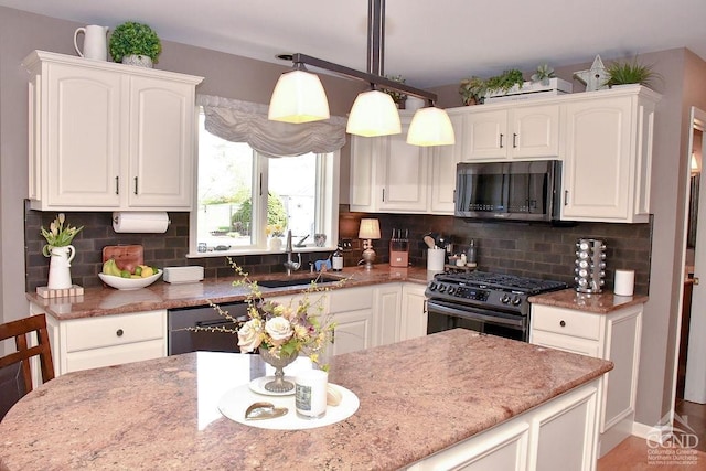 kitchen with white cabinetry, light stone countertops, a sink, and black appliances