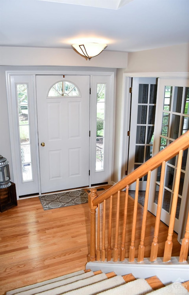 foyer entrance featuring plenty of natural light, light wood finished floors, and stairway