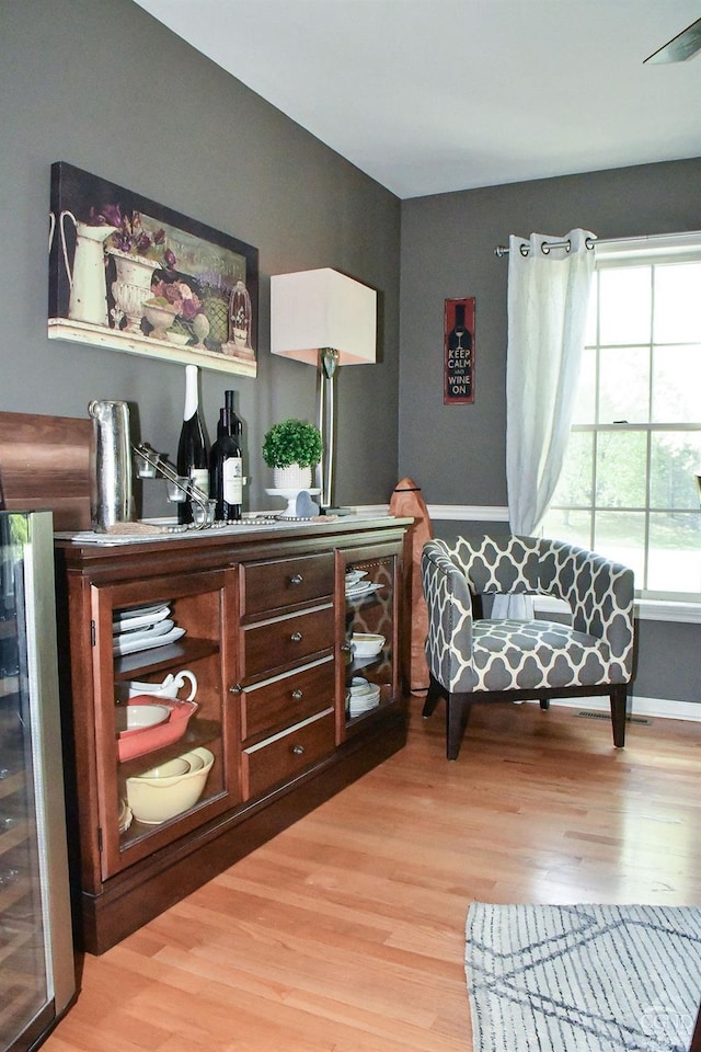 living area with beverage cooler and light wood-type flooring