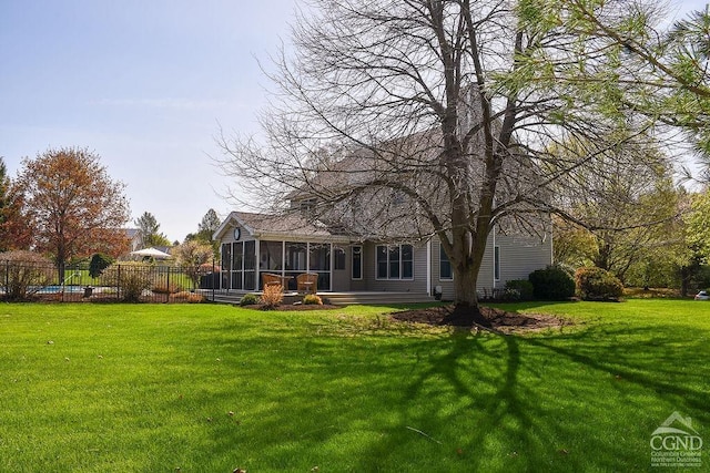 rear view of house featuring a sunroom, a lawn, and fence