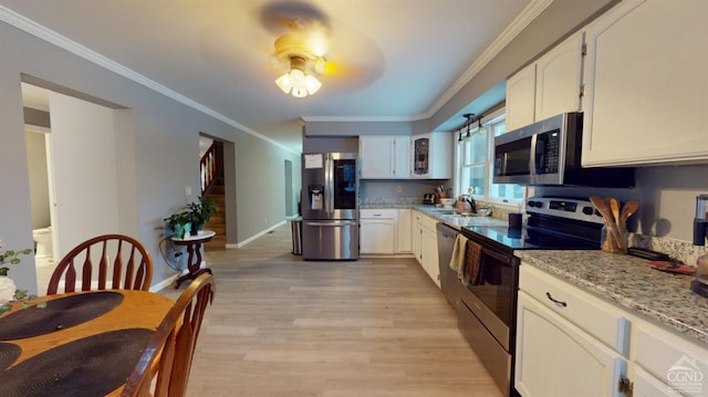 kitchen with stainless steel appliances, light stone countertops, sink, and white cabinets