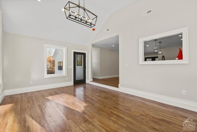 interior space with wood finished floors, visible vents, a chandelier, and baseboards