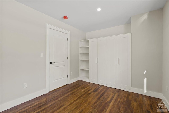 unfurnished bedroom with recessed lighting, baseboards, and dark wood-style flooring