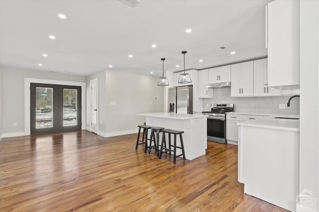 kitchen featuring a sink, french doors, appliances with stainless steel finishes, a kitchen bar, and a center island