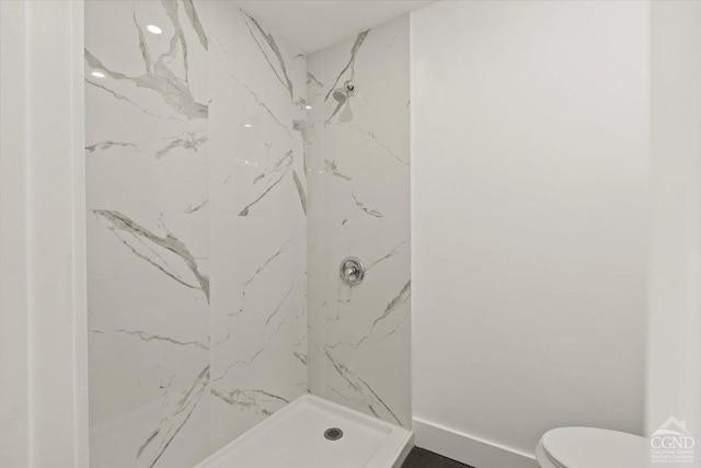 bathroom featuring toilet and a marble finish shower