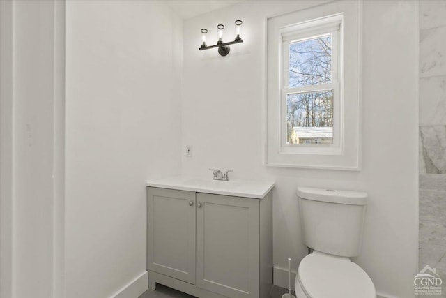 bathroom with toilet, vanity, and baseboards