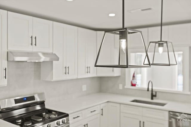 kitchen with under cabinet range hood, appliances with stainless steel finishes, white cabinets, and a sink