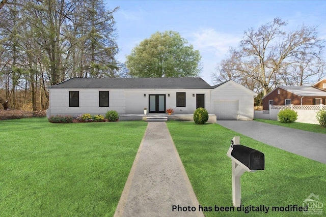 view of front of home with driveway, fence, french doors, a front yard, and a garage