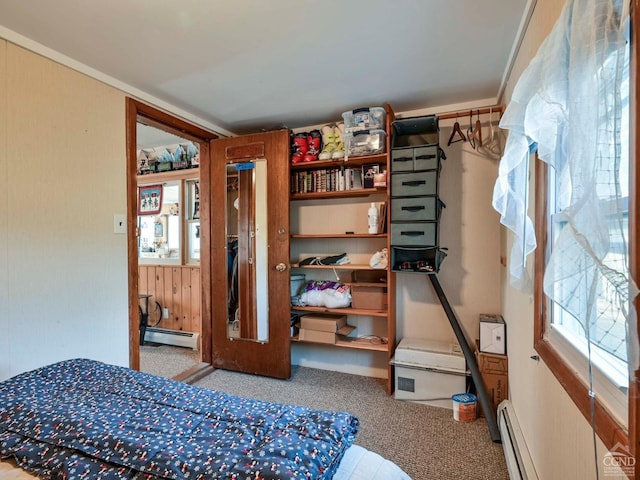 bedroom featuring wood walls, carpet floors, and a baseboard radiator