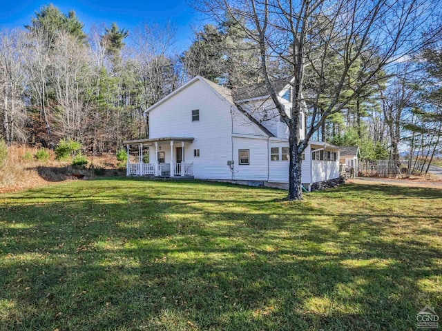 rear view of property featuring covered porch and a yard