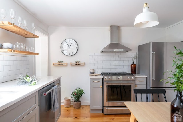 kitchen featuring open shelves, stainless steel appliances, gray cabinetry, light wood-style floors, and wall chimney range hood