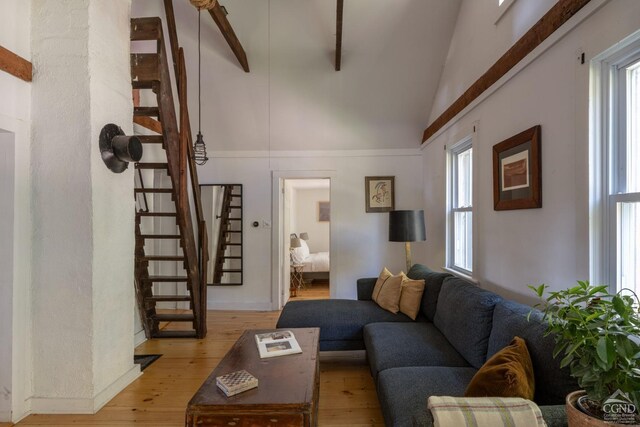 living area with stairs, lofted ceiling with beams, and light wood-style floors