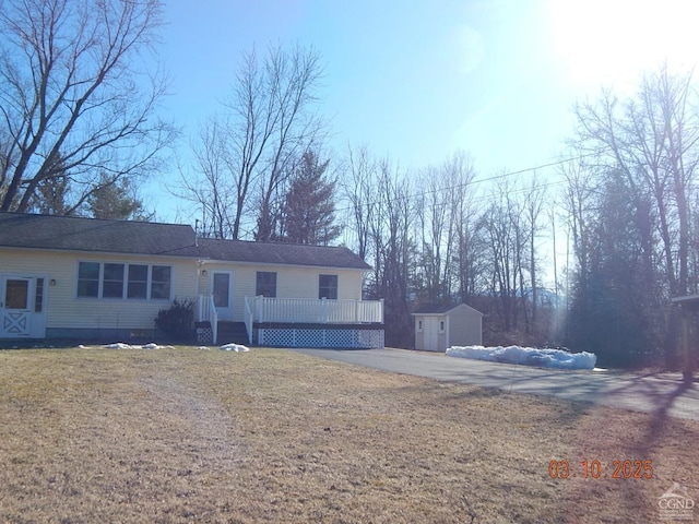 view of front of house featuring an outbuilding, a storage unit, a front lawn, and a wooden deck