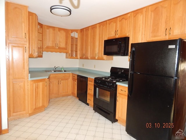 kitchen with a sink, light floors, black appliances, and light countertops