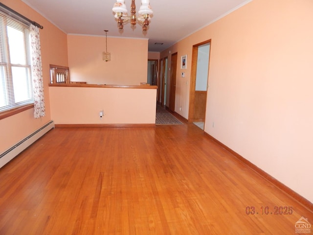 spare room with baseboards, ornamental molding, baseboard heating, wood finished floors, and a notable chandelier