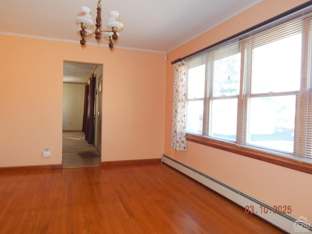 empty room with a baseboard heating unit, crown molding, wood finished floors, and baseboards