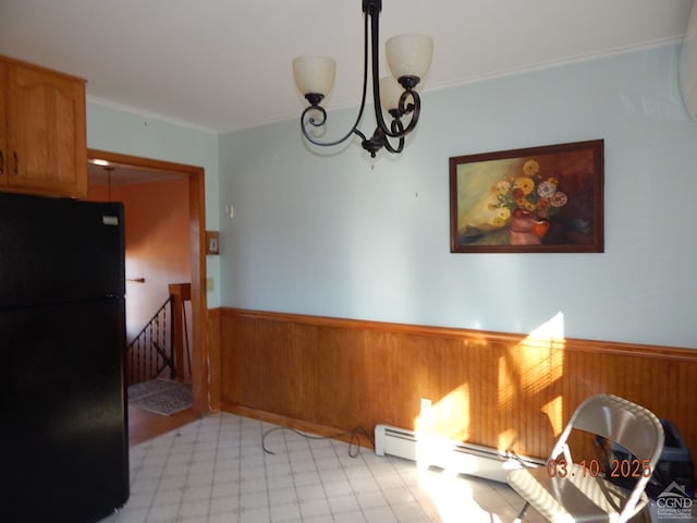 dining space featuring a chandelier, wooden walls, wainscoting, and ornamental molding