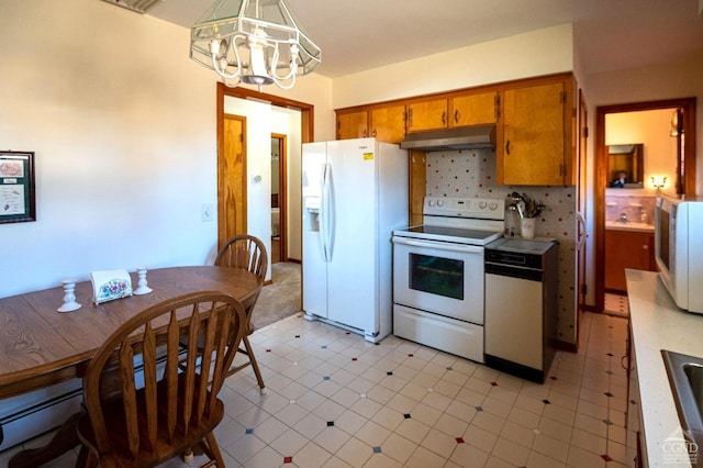 kitchen with brown cabinets, light floors, an inviting chandelier, white appliances, and under cabinet range hood