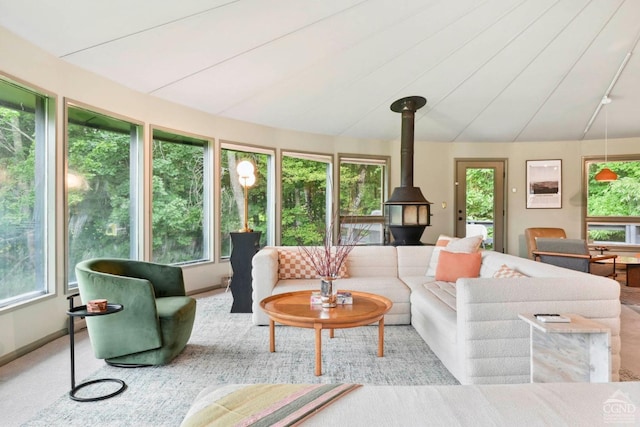 sunroom / solarium featuring lofted ceiling, a wood stove, and a healthy amount of sunlight