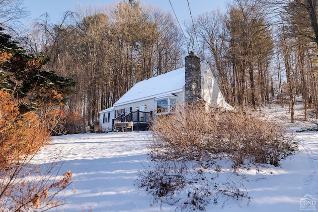 snow covered rear of property featuring a deck