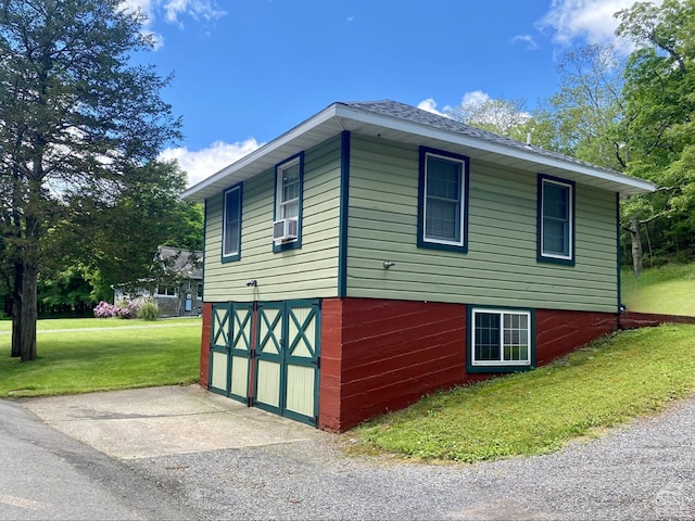 view of side of property with a garage, a yard, and cooling unit