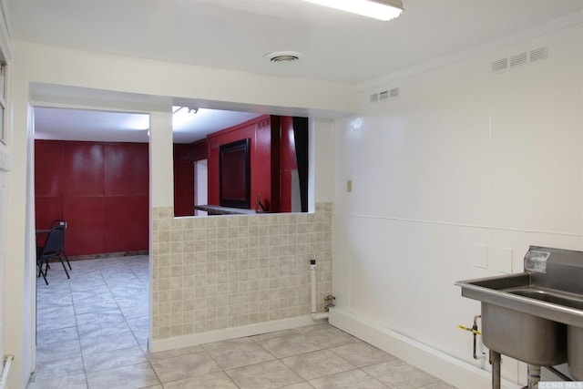 clothes washing area with sink, ornamental molding, and tile walls