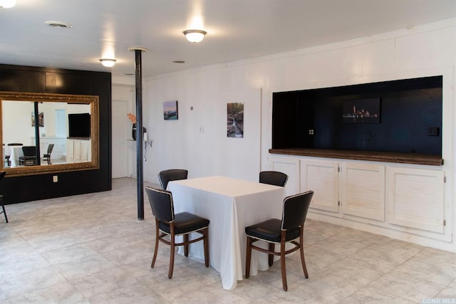 dining space featuring wooden walls and crown molding