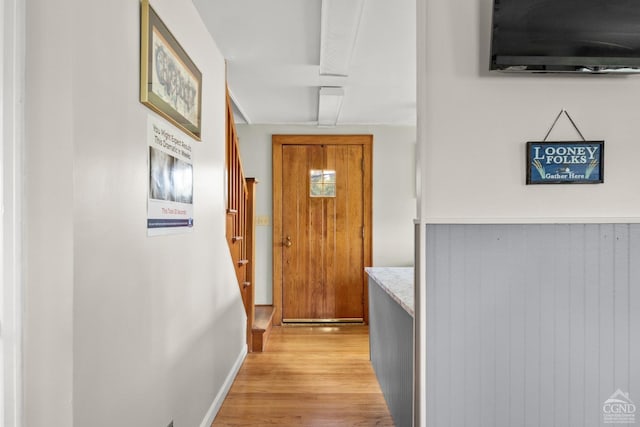 hall with light hardwood / wood-style flooring and wood walls