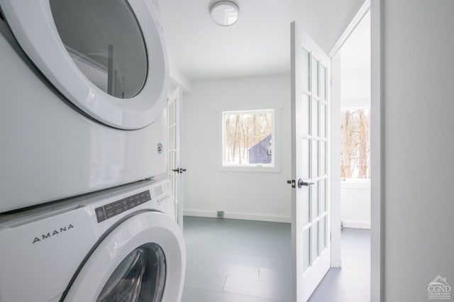 laundry room with stacked washer and dryer, laundry area, and baseboards