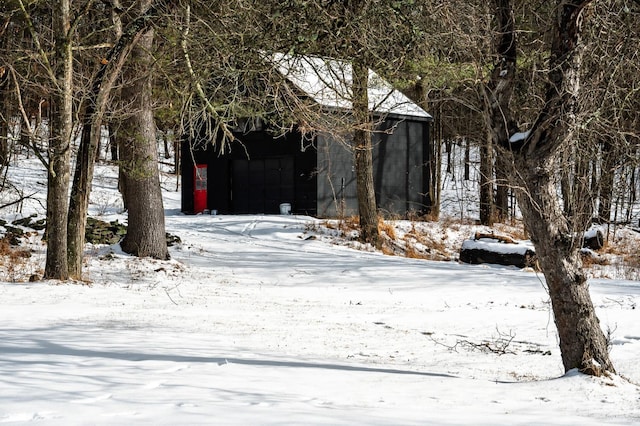 yard covered in snow featuring a garage and an outbuilding