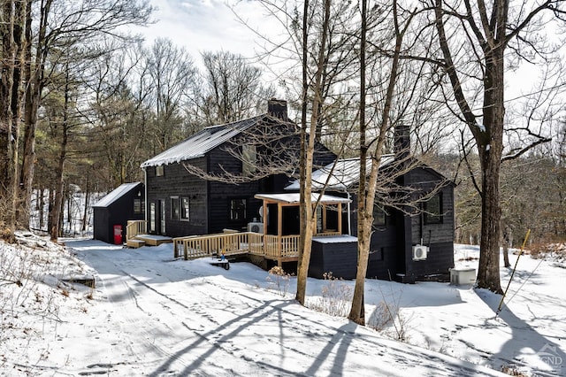 snow covered rear of property with a chimney