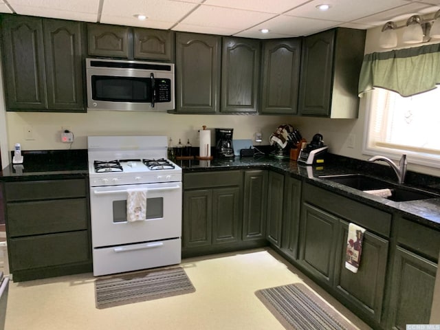 kitchen with white range with gas cooktop, sink, and dark stone counters