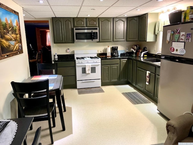 kitchen with green cabinets, sink, a drop ceiling, and appliances with stainless steel finishes