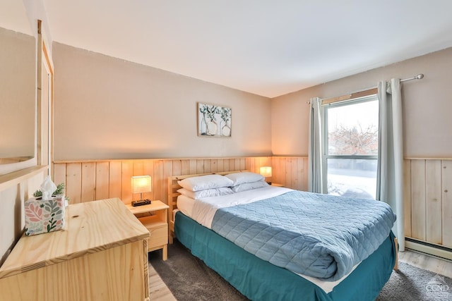 bedroom with dark wood-type flooring, a baseboard radiator, and wooden walls