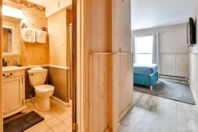 bathroom featuring vanity, wooden walls, a baseboard radiator, hardwood / wood-style flooring, and toilet