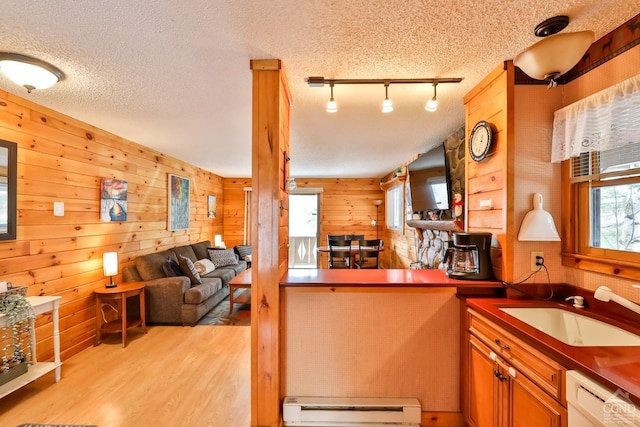 kitchen with wood walls, rail lighting, sink, baseboard heating, and a textured ceiling