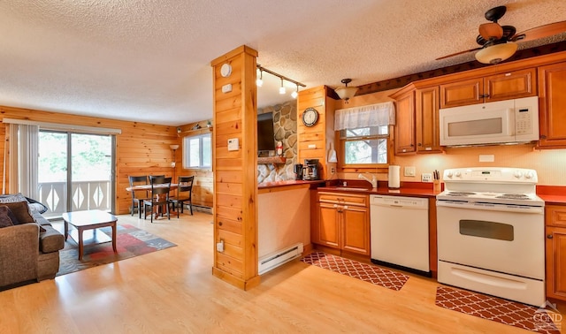 kitchen featuring ceiling fan, baseboard heating, wood walls, a textured ceiling, and white appliances