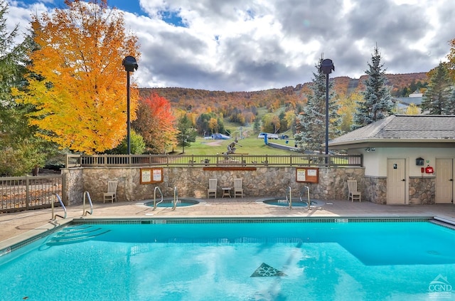 view of pool featuring a mountain view, a community hot tub, and a patio