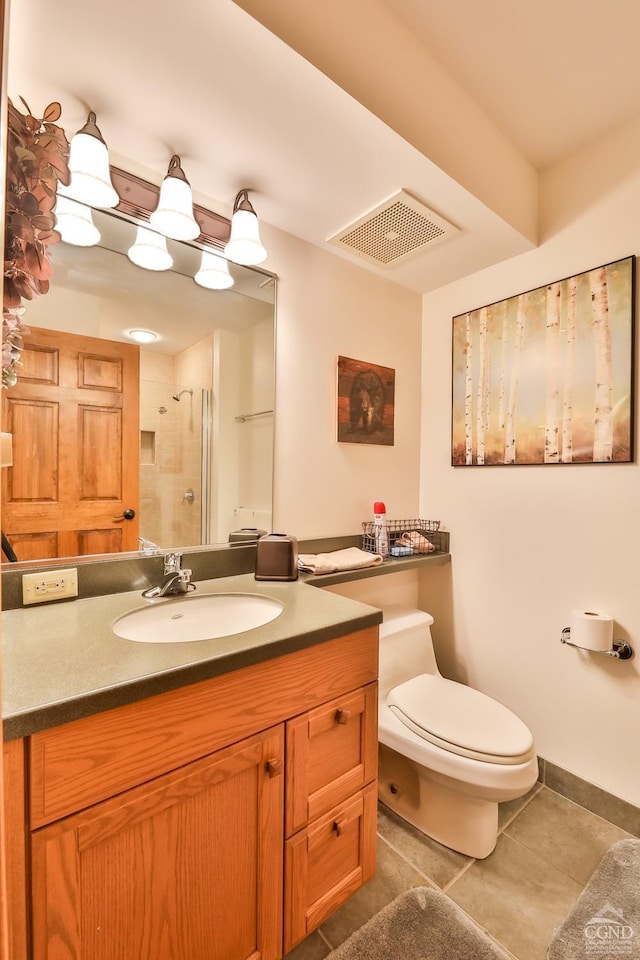 bathroom with tile patterned flooring, a tile shower, vanity, and toilet