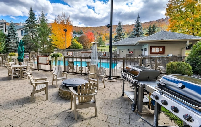 view of patio with area for grilling, a mountain view, and a community pool