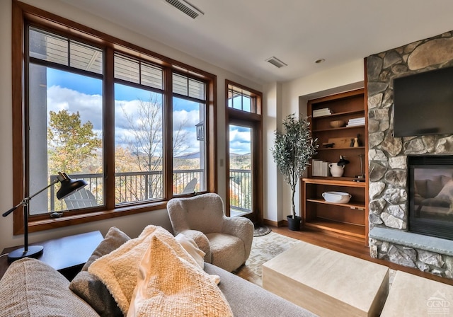 sitting room featuring hardwood / wood-style flooring, built in shelves, and a fireplace