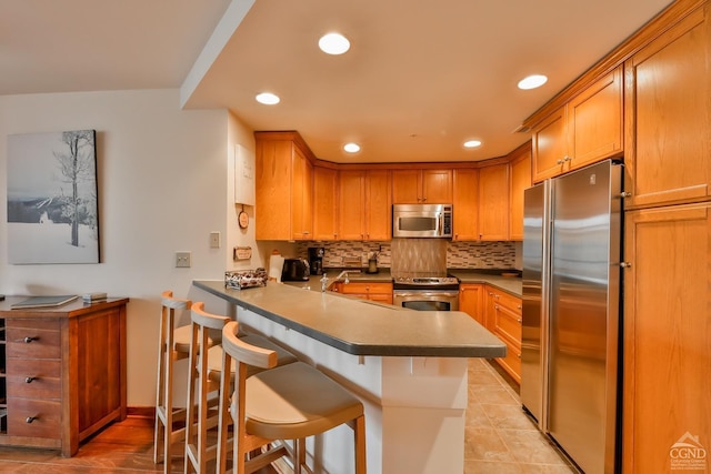 kitchen with a kitchen breakfast bar, kitchen peninsula, backsplash, and appliances with stainless steel finishes