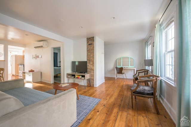 living room with a wall mounted air conditioner, light hardwood / wood-style floors, and a wealth of natural light