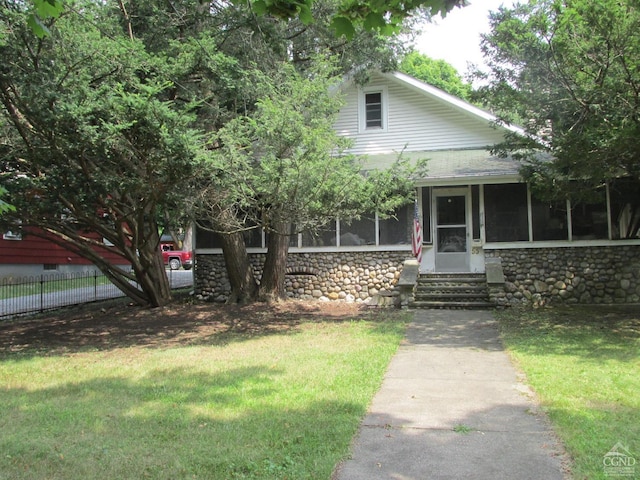 view of front of home with a front yard and a sunroom