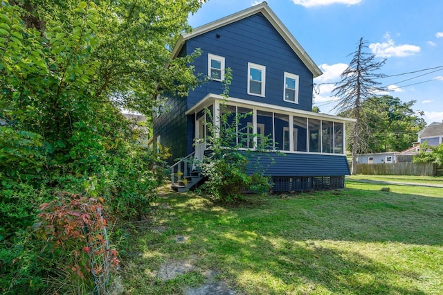 rear view of property with a lawn and a sunroom