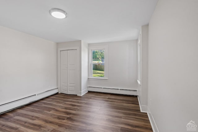 unfurnished room with dark wood-type flooring and a baseboard heating unit