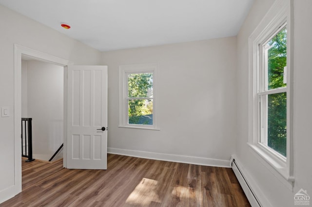 unfurnished bedroom with dark hardwood / wood-style floors, a baseboard radiator, and multiple windows