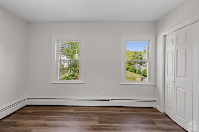 unfurnished room featuring a healthy amount of sunlight, dark hardwood / wood-style flooring, and baseboard heating