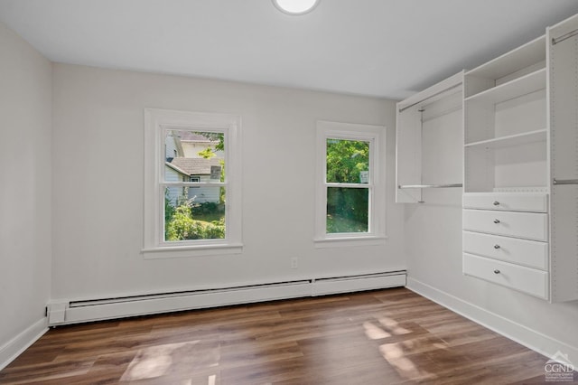 spare room with dark hardwood / wood-style floors and a baseboard heating unit